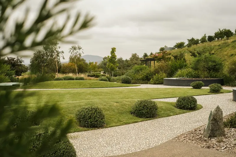 Jardin paysager contemporain avec pelouse, allée de gravier et arbustes taillés en boule